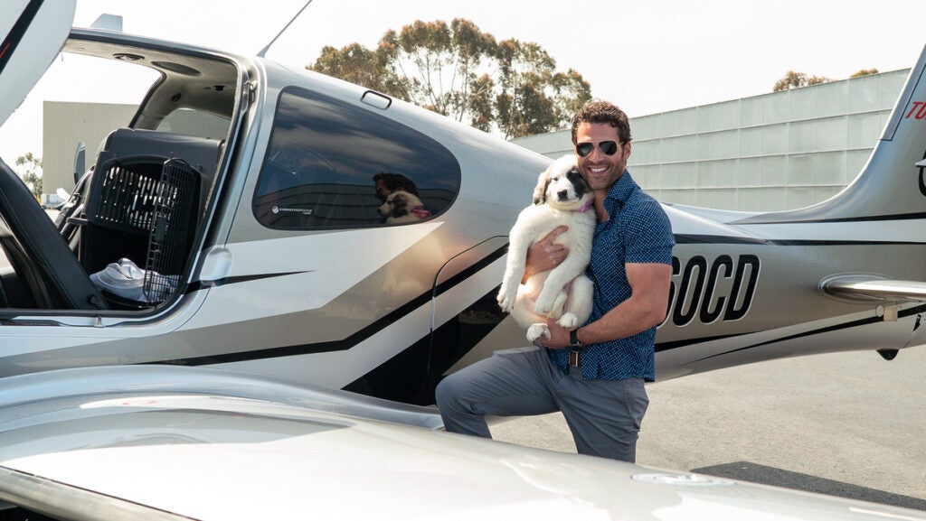 man and dog posing in front of a car