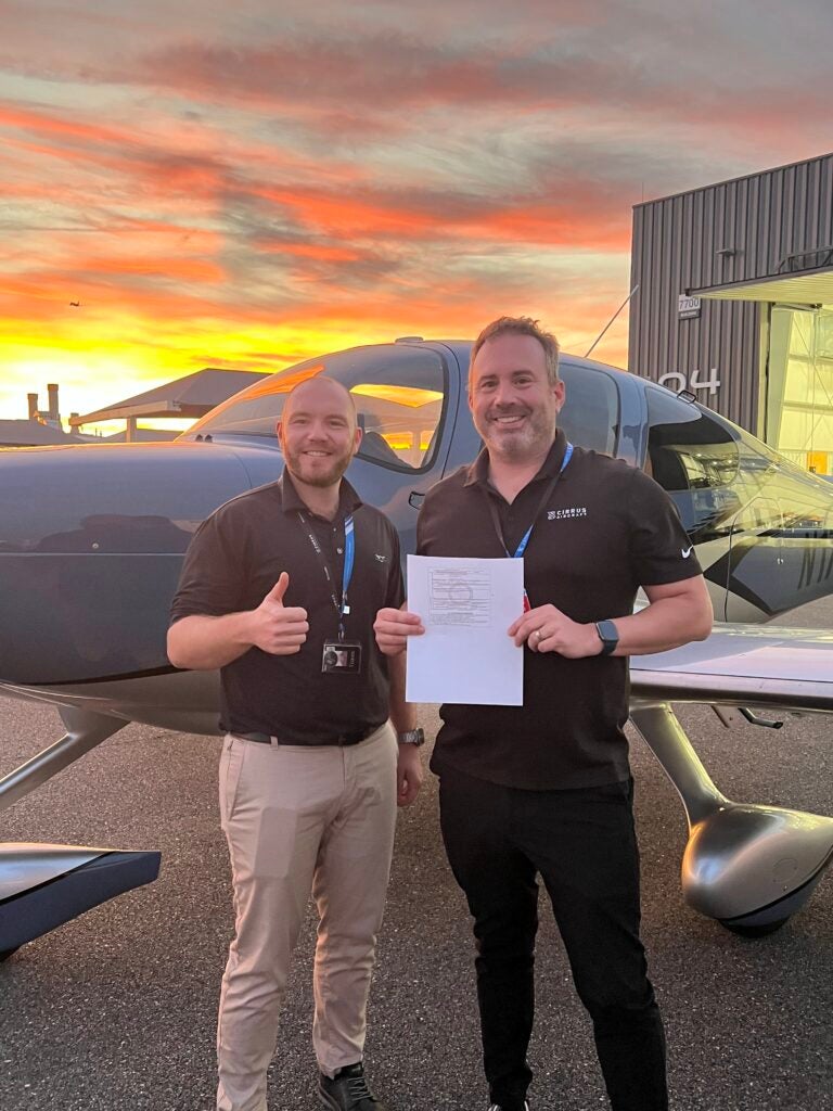 student and examiner in front of cirrus aircraft