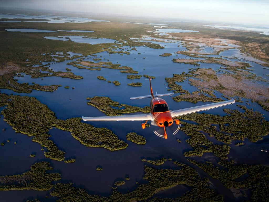 orange SR Series 2026 Cirrus air-to-air flying over swamp