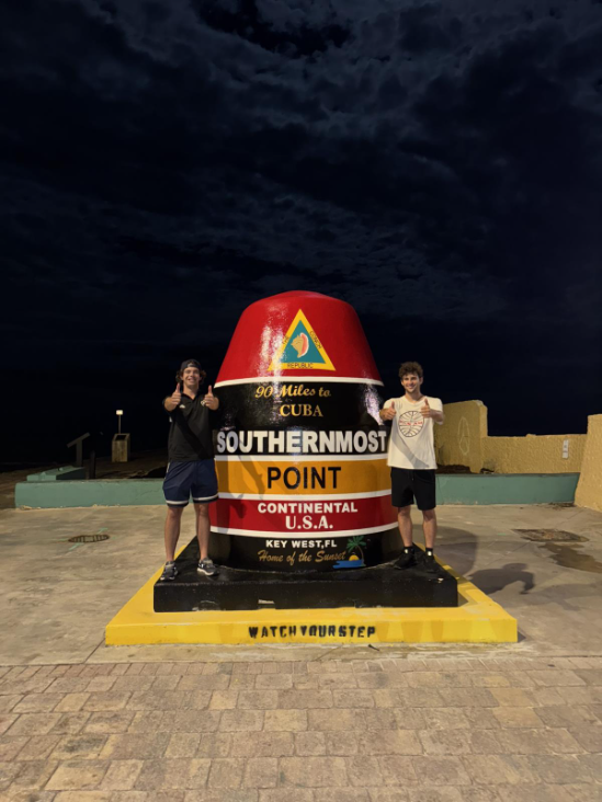 two young men standing next to the most souther point in continental USA