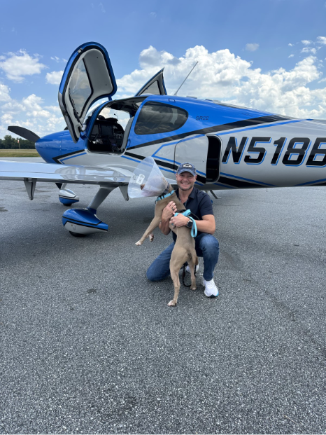 man and dog posing next to blue SR Series aircraft 
