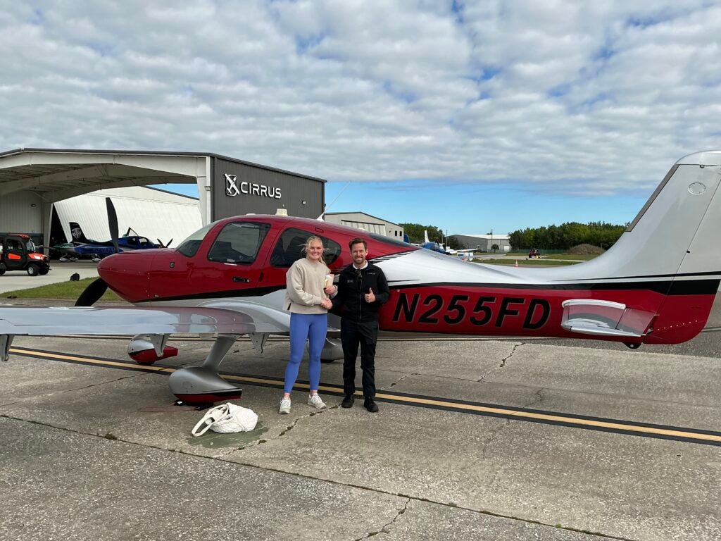 man and women shaking hands in front of Cirrus SR Series 22 