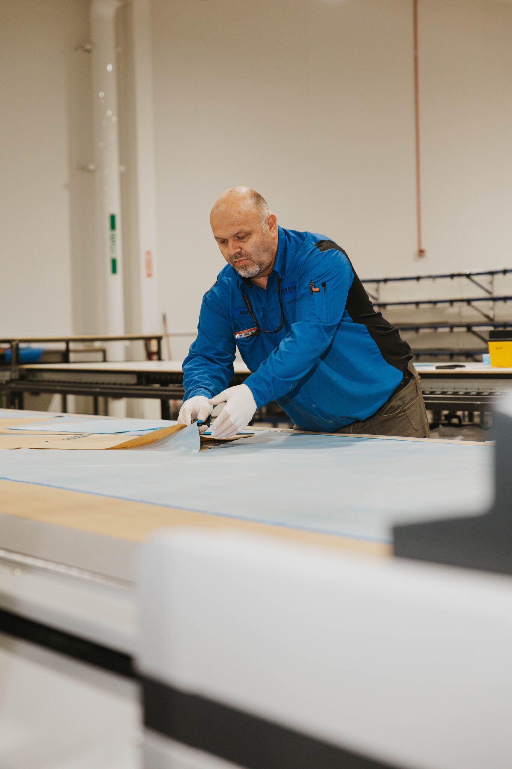 Cirrus team member laying up composite material at a work table inside the Grand Forks manufacturing facility