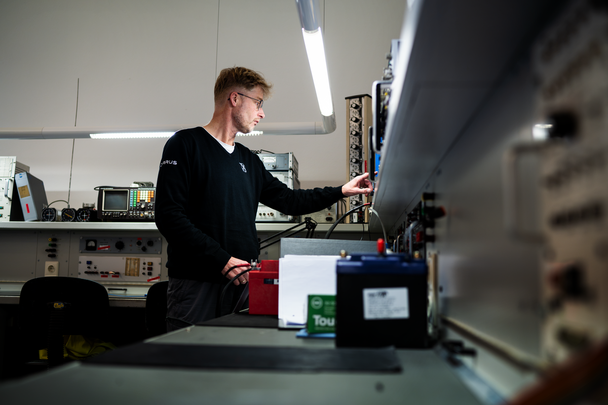 Avionics technician testing equipment at a workbench in a Cirrus service center